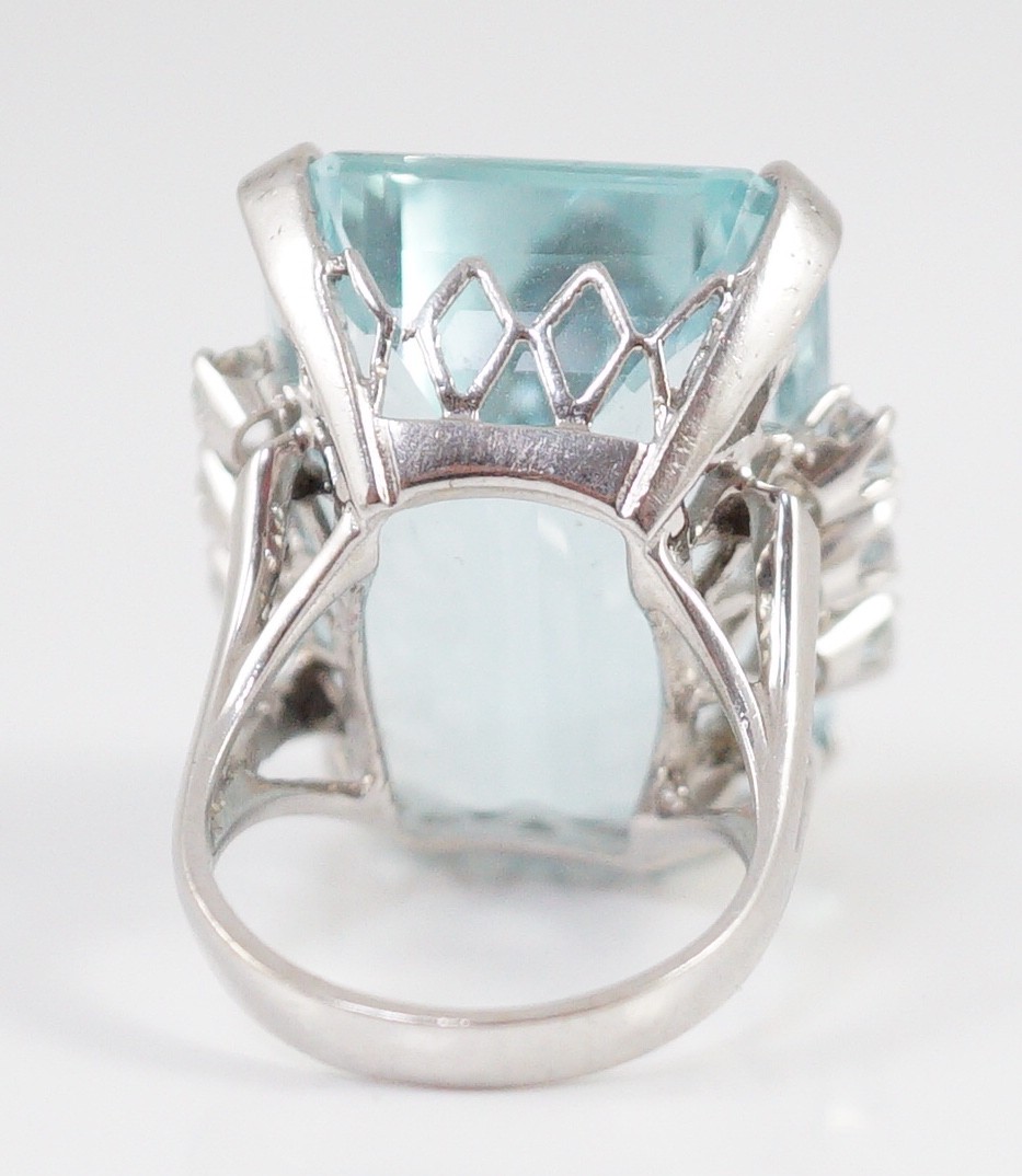A large modern 14k white gold and emerald cut aquamarine set dress ring, flanked by six round cut diamonds